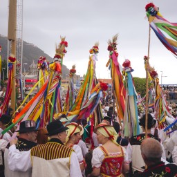 Una multitud de gente vestida con traje tradicional canario y adornos muy coloridos celebrando la romería de San Isidro.